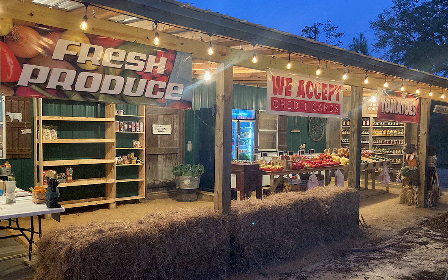 open-air store front of nana and papa's, at dusk, with vegetables, fruit, and other market items
