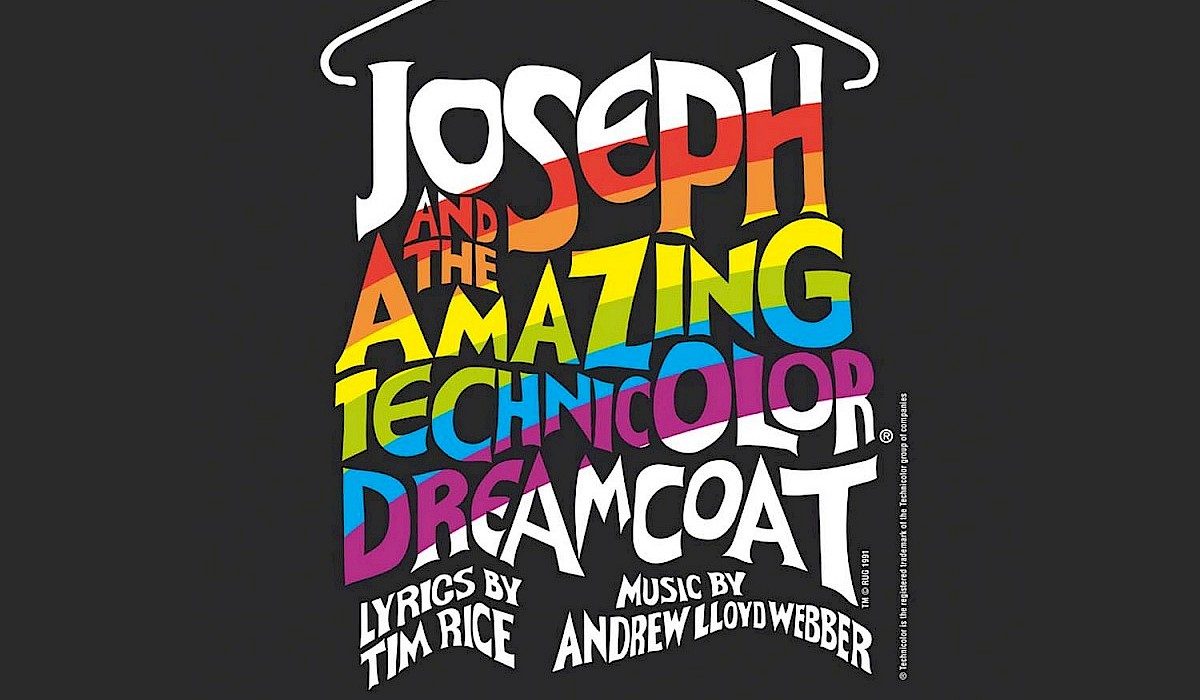 rainbow dreamcoat hanging on a white hanger on a black background