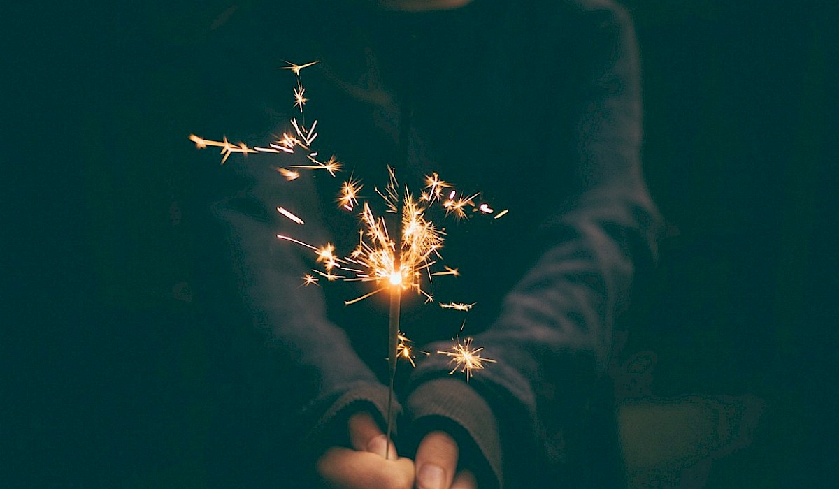 child in a sweater holding a sparkler